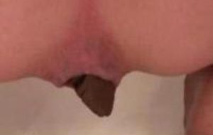 Gros plan sur anus de femme qui chie dans une baignoire